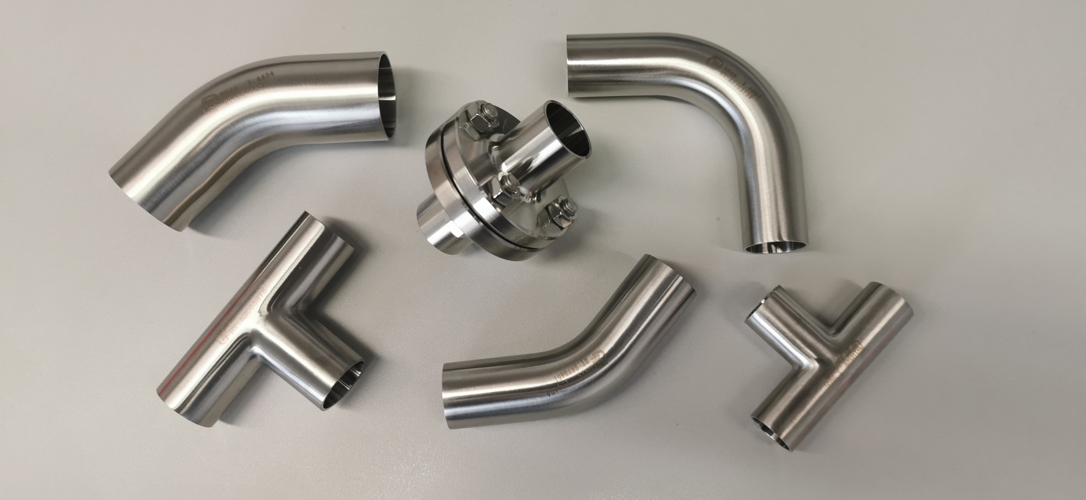 Edelstahl-Rohrbögen, T-Stücke und eine Flanschverbindung aus dem Sortiment von AZ Fittings